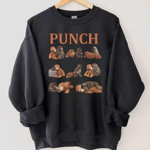 May include: Black sweatshirt with the word "PUNCH" in orange block letters. The sweatshirt features a repeating pattern of cartoon monkeys in various poses. The monkeys are in shades of brown and gray.
