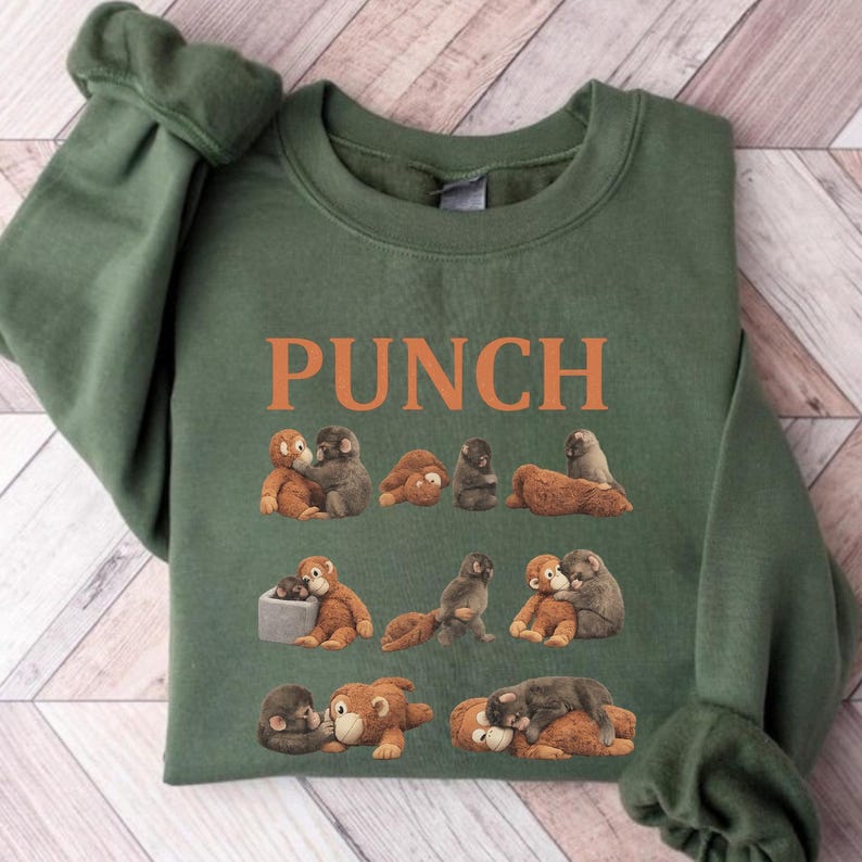 May include: Green sweatshirt with the word "PUNCH" in orange block letters. The sweatshirt features a repeating pattern of cartoon monkeys in various poses. The monkeys are in shades of brown and gray.