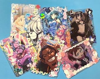 Op de afbeelding: Een verzameling anime-achtige karakterkaarten met decoratieve randen. Elke kaart toont een andere karakterillustratie, met levendige kleuren en gedetailleerde kunstwerken. De kaarten zijn gerangschikt op een lichtblauwe ondergrond.