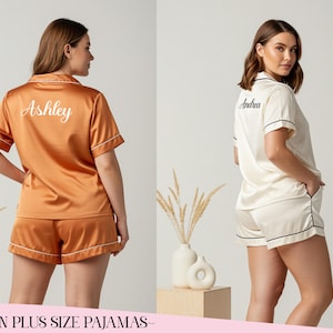 May include: Satin plus size pyjamas in burnt orange and ivory. The burnt orange set has the name "Ashley" embroidered on the back. The ivory set has the name "Andrea" embroidered on the back. Both sets have white piping.