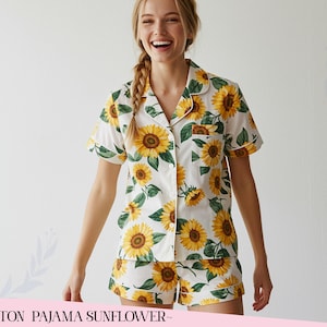 May include: A white cotton pajama set featuring a sunflower pattern. The set comprises a short-sleeved shirt with buttons and matching shorts. The shirt has a pocket and white trim. The text at the bottom reads "COTTON PAJAMA SUNFLOWER".