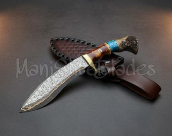 May include: A Damascus steel kukri knife with a patterned blade, a brown and blue handle, and a leather sheath. The knife has a curved blade and a decorative handle. The text "Manis Blades" is visible.