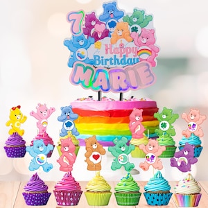May include: A rainbow-layered birthday cake with a topper that reads "Happy Birthday MARIE" and the number 7, surrounded by Care Bear figures. Cupcakes with Care Bear toppers in various colors are arranged in front.