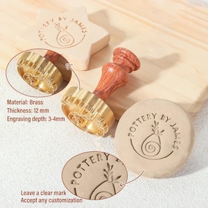 May include: A brass pottery stamp with a wooden handle, featuring a circular head with a spiral and leaf design and the text POTTERY BY JAMES. The stamp has a thickness of 12 mm and an engraving depth of 3-4 mm, shown creating impressions in clay.