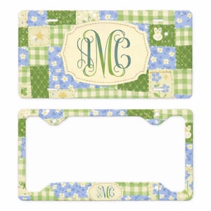 May include: License plate and frame set with a patchwork design in shades of blue, green, and cream. The license plate features a large, ornate initial "M" in green and blue within a cream-colored oval.