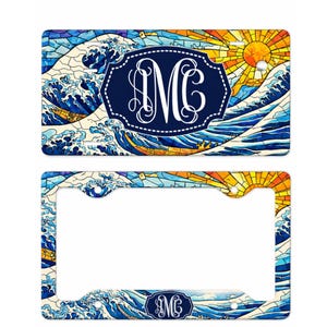 May include: A license plate and license plate frame featuring a stained-glass design of ocean waves and a setting sun. The design includes a navy blue oval with the white monogram "MC".