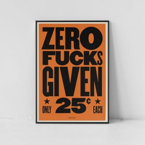 May include: A framed poster with the text "ZERO FUCKS GIVEN" in large, bold, black letters on an orange background. Below the text are the words "ONLY 25¢ EACH" with star symbols. The poster has a black frame.