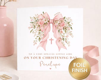 May include: A square greeting card featuring a large pink ribbon bow adorned with pink roses and green foliage. A small pink cross is centered below the bow. The text reads: TO A VERY SPECIAL LITTLE GIRL ON YOUR CHRISTENING DAY, Penelope, 09.01.2026.