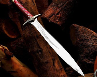 May include: A silver sword with a red and silver handle, set against a backdrop of wooden logs. The blade features an etched design. The handle has a red grip with silver detailing. A fantasy-themed item.