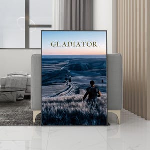Könnte beinhalten: Gerahmter Druck mit einer Landschaftsszene und dem Wort "GLADIATOR" in Gold. Das Bild zeigt eine Person, die über ein Tal blickt. Der Druck wird in einem modernen Wohnzimmer präsentiert.