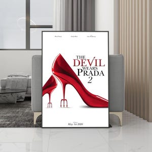 May include: A framed poster with the title "The Devil Wears Prada 2" and a pair of red high heels. The stiletto heels are designed as tridents. The poster's release date is May 1st, 2026. The poster is in a black frame.