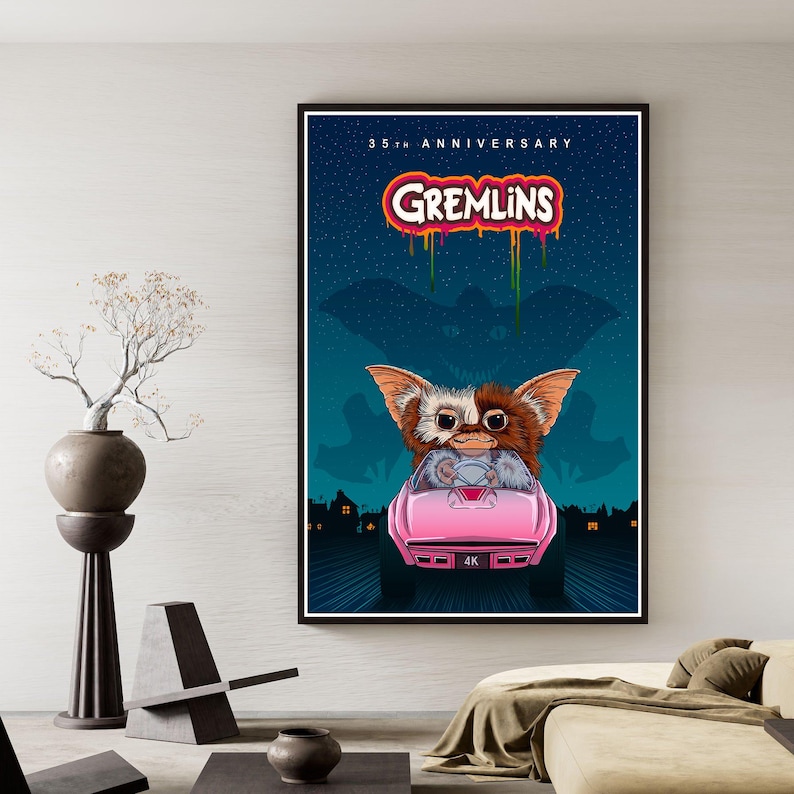 Puede incluir: Un p&oacute;ster enmarcado con una escena de la pel&iacute;cula Gremlins. La obra de arte muestra a un Gremlin conduciendo un coche rosa, con el texto "Gremlins" en una fuente goteante. El fondo es un cielo nocturno azul oscuro con un paisaje urbano.