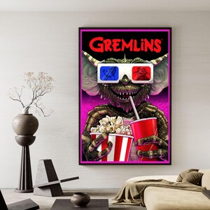 Puede incluir: Un p&oacute;ster enmarcado con un personaje de Gremlins con gafas 3D, sosteniendo palomitas de ma&iacute;z y una bebida. El p&oacute;ster tiene un borde negro con la palabra "GREMLINS" en letras rojas. El fondo es rosa brillante.