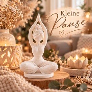 May include: A white figurine of a person in a seated yoga pose with arms raised above the head. The figure has a bun hairstyle and wears a top and pants. The text "Kleine Pause" with a heart symbol is visible in the upper right corner.