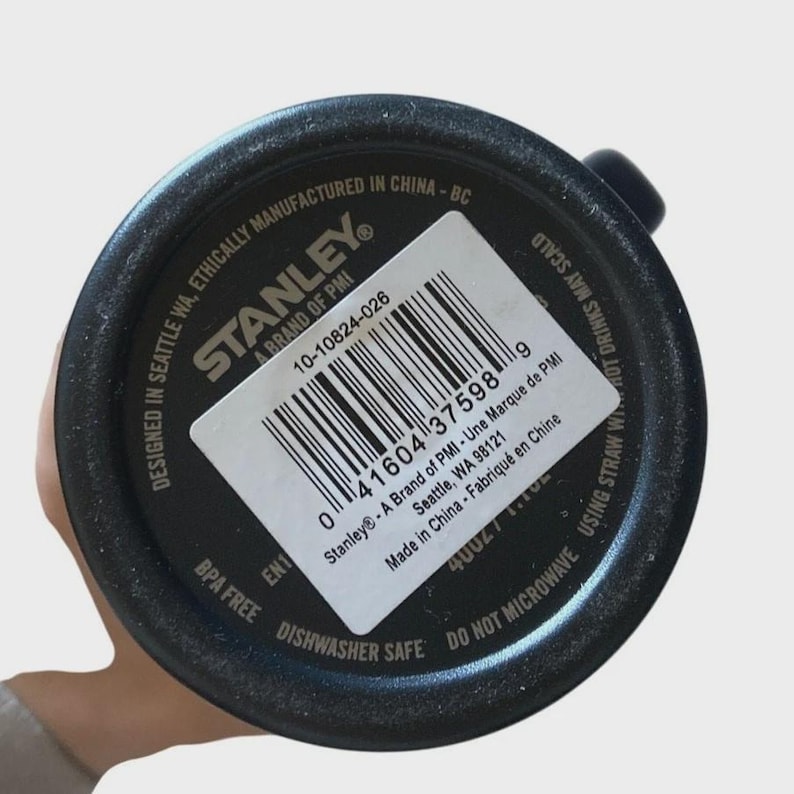 May include: Black Stanley brand tumbler base with a white label. The label includes a barcode and text that reads "Designed in Seattle WA, Ethically Manufactured in China". The tumbler is BPA free and dishwasher safe.