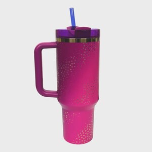 May include: A bright pink insulated travel mug with a handle, a purple lid, and a blue straw. The mug features a pattern of small, gold-coloured stars. A gold band accents the top of the mug.