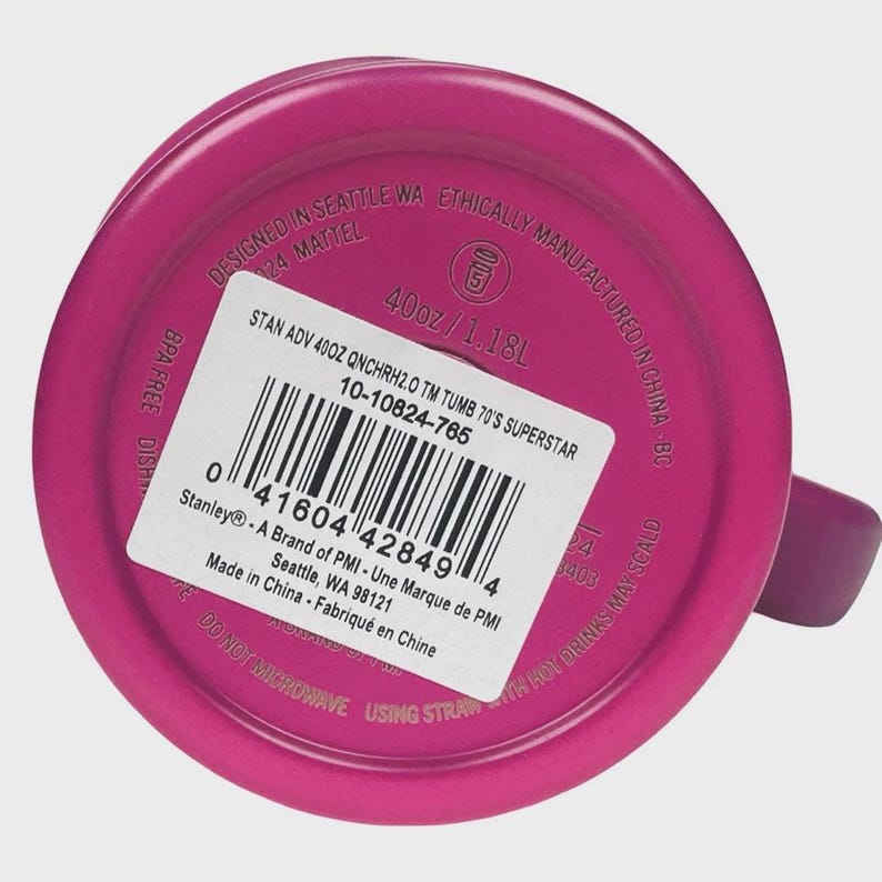 May include: A magenta-coloured tumbler with a handle. The base of the tumbler features a white sticker with product information, including the text "40oz / 1.18L" and "BPA FREE". The text "Designed in Seattle WA" is also visible.
