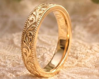 May include: A gold ring with an intricate floral pattern. The ring is set against a soft, cream-colored lace background. The ring's design features detailed carvings and a polished finish, showcasing a classic and elegant style.