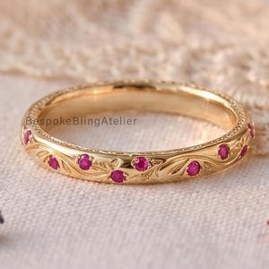 Anello in argento con incisioni floreali e rubini rosa sintetici rotondi sparsi.