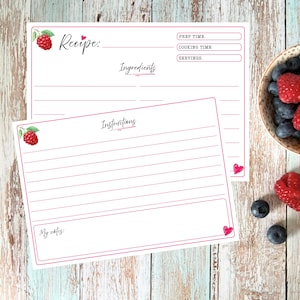 May include: Two white recipe cards with pink borders and raspberry illustrations. The top card features fields for Recipe, Prep Time, Cooking Time, Servings, and Ingredients. The bottom card includes an Instructions section and a My notes box.