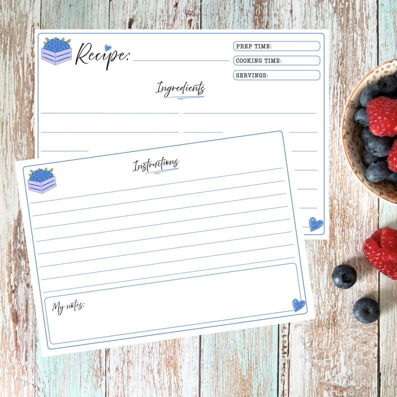 May include: Two white recipe cards with blue borders and blueberry crate illustrations. The top card features fields for Recipe, Prep Time, Cooking Time, Servings, and Ingredients. The bottom card includes an Instructions section and a My Notes box.