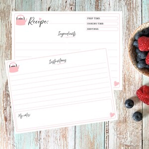 May include: Two white recipe cards with pink borders and a small pink kettle illustration. The top card features fields for Recipe, Prep Time, Cooking Time, Servings, and Ingredients. The bottom card includes an Instructions section and a My notes area.