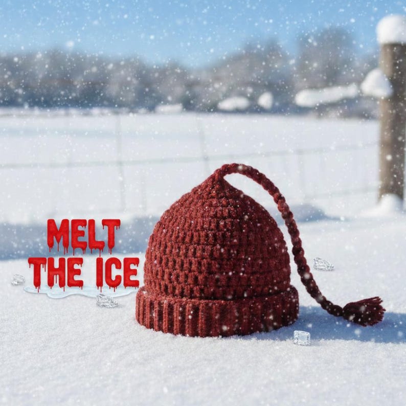 K&ouml;nnte beinhalten: Eine bordeauxfarbene H&auml;kelm&uuml;tze mit einer langen geflochtenen Quaste, die im Schnee liegt. Der Text "MELT THE ICE" wird in roten, tropfenden Buchstaben angezeigt. Die Szene spielt sich im Freien mit einem verschneiten Hintergrund ab.