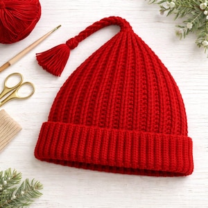 May include: A bright red knitted hat with a long, braided tassel. The hat has a ribbed design and a folded brim. The tassel is attached to the top of the hat. The hat is likely handmade and is a winter accessory.