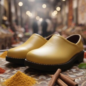 Könnte beinhalten: Ein Paar gelbe Lederclogs mit schwarzen Sohlen. Die Schuhe werden auf einer dekorativen Oberfläche mit Gewürzhaufen und Zimtstangen präsentiert. Der Hintergrund ist verschwommen und deutet auf eine Marktumgebung hin.