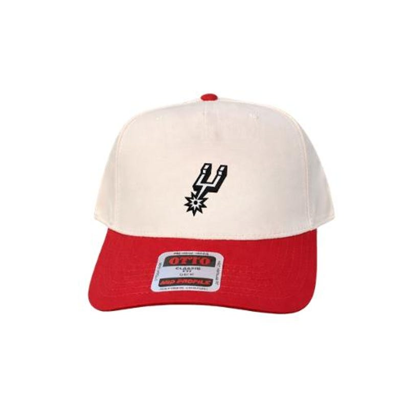 May include: A baseball cap with an off-white crown and a red brim. The front features a black embroidered spur logo. A rectangular sticker on the brim displays the text OTTO CLASSIC FIT MID PROFILE in black and red lettering on a white background.