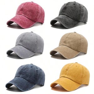 May include: A collection of six baseball caps in various colors including red, charcoal gray, light gray, tan, navy blue, and yellow. Each cap features a distressed, washed-out fabric finish, a curved brim with stitched detailing, and a button top.