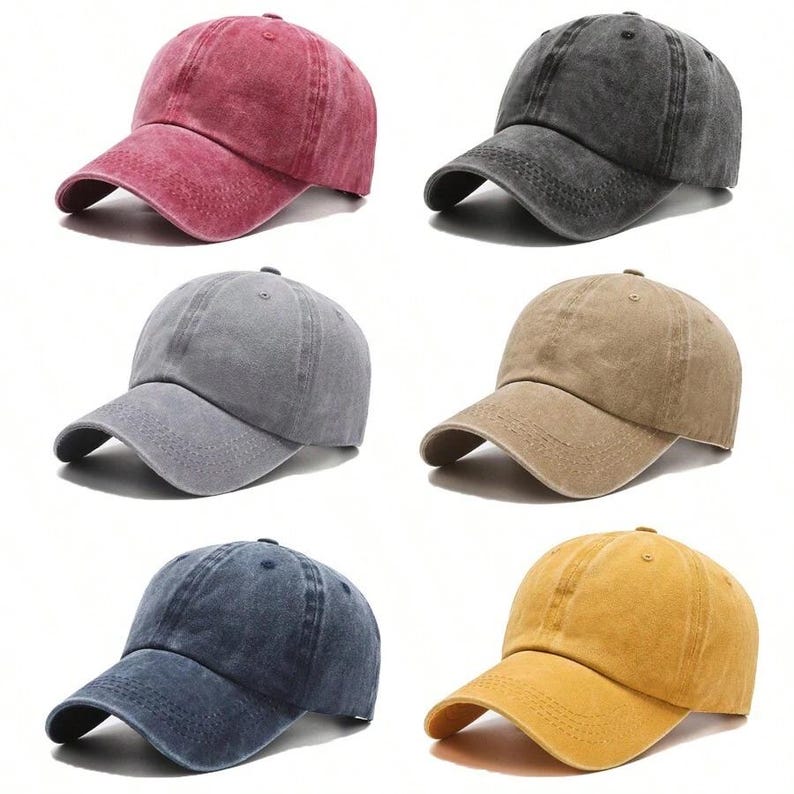 May include: A collection of six baseball caps in various colors including red, charcoal gray, light gray, tan, navy blue, and yellow. Each cap features a distressed, washed-out fabric finish, a curved brim with stitched detailing, and a button top.