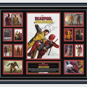 May include: Framed artwork of the film "Deadpool & Wolverine." The central image depicts the characters in a fight, surrounded by smaller images. The black frame has a red border, and the artwork includes signatures and movie text.