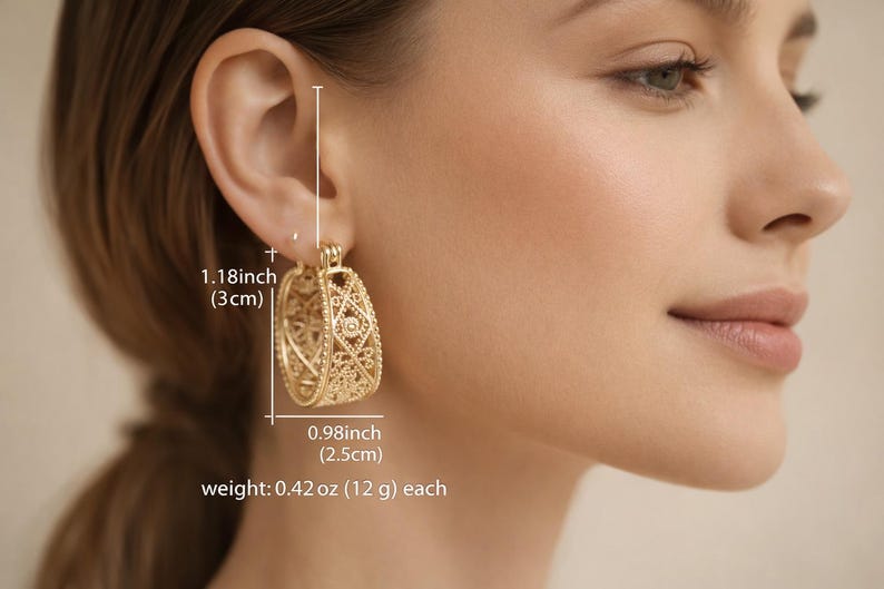 May include: Gold-toned filigree hoop earrings. Each earring is 1.18 inches (3 cm) long and 0.98 inches (2.5 cm) wide, weighing 0.42 oz (12 g). The earrings feature an openwork design with intricate patterns, showcasing a delicate and ornate style.