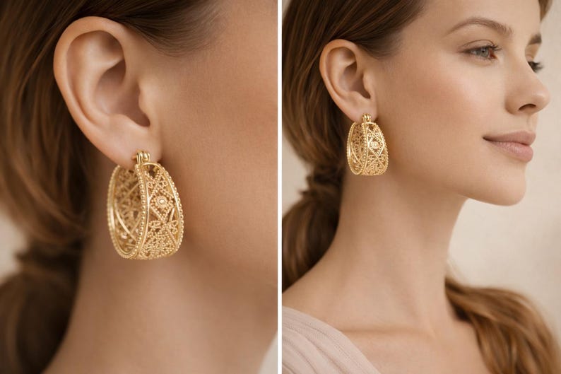 May include: Gold-colored filigree hoop earrings. The earrings have an oval shape with intricate openwork designs. The earrings are worn by a person with light skin and brown hair. The earrings are a classic jewelry piece.