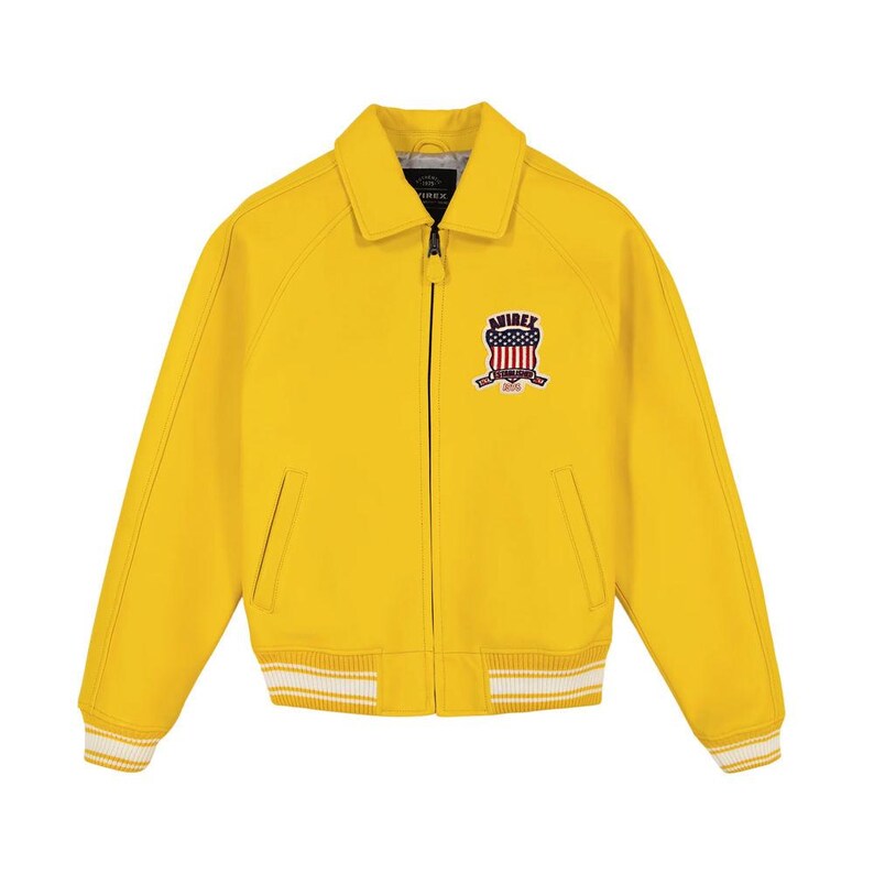 May include: A bright yellow zip-up jacket featuring a classic collar, long sleeves, and ribbed cuffs and hem with white stripes. On the left chest, there is a patch displaying the text AVIREX above a shield graphic with red and white stripes.