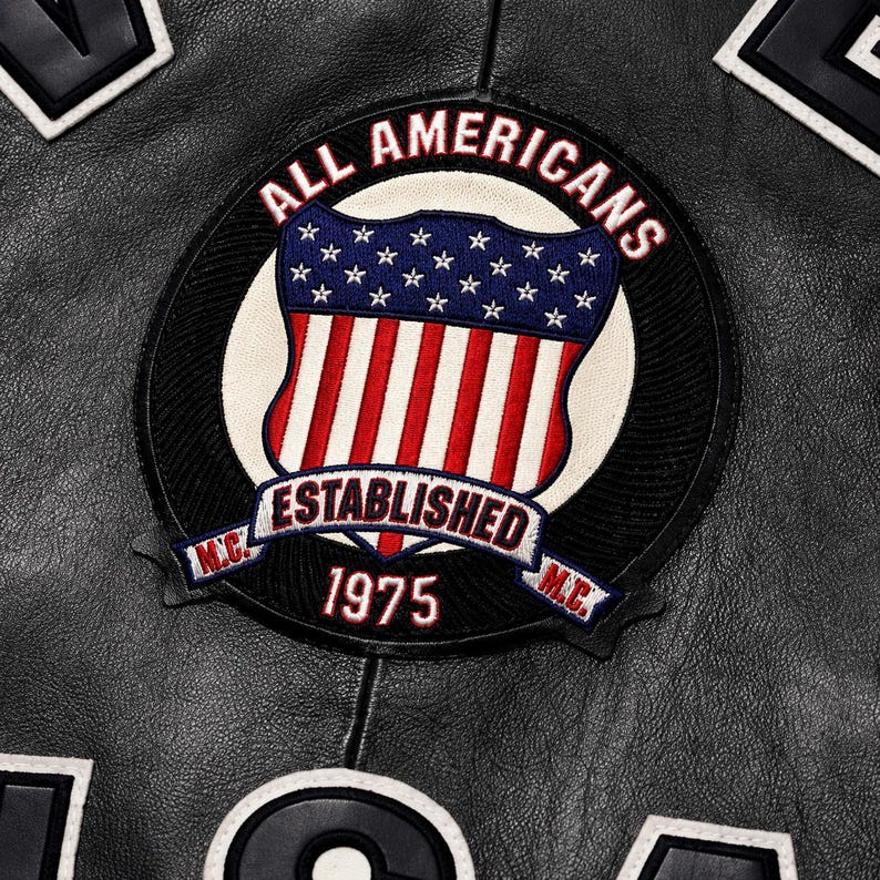 May include: A black leather jacket featuring a circular embroidered patch. The patch displays the text ALL AMERICANS, ESTABLISHED 1975, and M.C. surrounding a shield with a blue field of white stars above red and white vertical stripes.