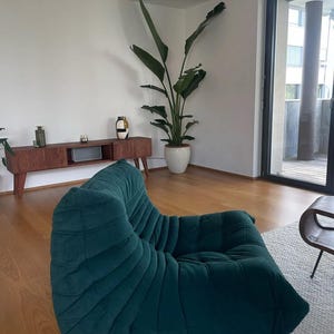 Puede incluir: Una taza de cer&aacute;mica blanca con un asa negra y el texto "But First, Coffee" en negrita negra. La taza se encuentra sobre un fondo borroso, sugiriendo un ambiente acogedor.