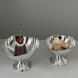 Può includere: Un set di tre tazze in ceramica con una glassa screziata color crema. Ogni tazza presenta un design dipinto a mano diverso: una foglia blu e verde, un fiore giallo e una bacca rossa. Le tazze hanno un design semplice e moderno.