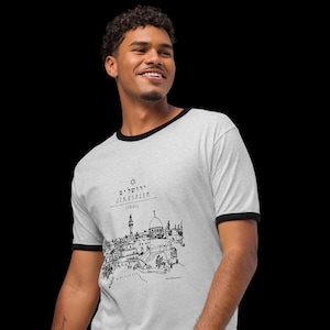 May include: A light gray ringer t-shirt with black trim featuring a black and white illustration of Jerusalem. The text "Jerusalem" is above the illustration, with "Israel" below it.