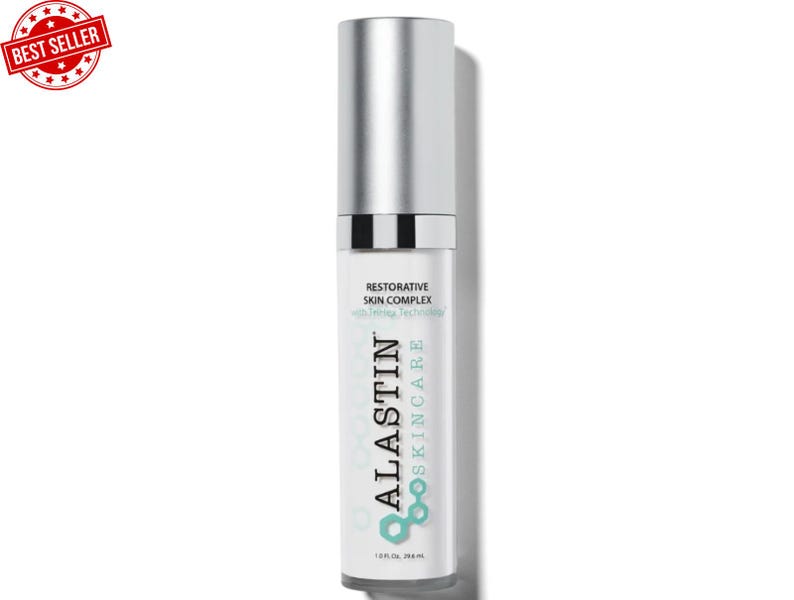 May include: A white and silver skincare product bottle with the text "ALASTIN SKINCARE" and "RESTORATIVE SKIN COMPLEX". The bottle has a silver cap and a "BEST SELLER" sticker in the upper left corner. The bottle contains 1.0 fl oz / 29.6 mL.