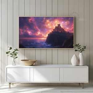May include: A framed art print shows a castle on a cliffside at sunset, overlooking the ocean. The sky is a mix of purple, orange, and yellow, with fireworks above the castle. The artwork is displayed on a white cabinet, with decorative vases.