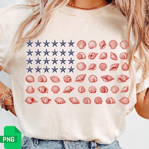 May include: A cream-colored t-shirt featuring a graphic design of an American flag composed of blue starfish in the canton area and rows of various red seashells forming the stripes. The design is centered on the front of the garment.