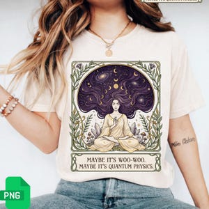 May include: Beige t-shirt featuring a graphic of a woman meditating with long purple hair, a starry sky, and crystals. The text reads "MAYBE IT'S WOO-WOO. MAYBE IT'S QUANTUM PHYSICS." The design is framed with green and gold botanical elements.