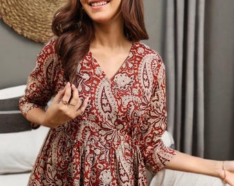 Könnte beinhalten: Burgunderrotes und cremefarbenes Paisley-Kleid mit V-Ausschnitt und Dreiviertelärmeln. Das Kleid hat ein figurbetontes Oberteil und einen fließenden Rock. Der Stoff hat ein detailliertes Blumenmuster. Das Kleid ist ein lässiger Stil.