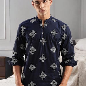 Puede incluir: Camisa azul marino de manga larga con cuello mandarín y estampado geométrico blanco. La camisa tiene una botonadura frontal y mangas enrolladas. La camisa está hecha de un material suave y cómodo.