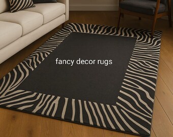 Pode incluir: Um tapete retangular com um painel central preto sólido rodeado por uma borda larga com um padrão de listras de zebra em bege e preto. O texto "fancy decor rugs" está impresso em branco na seção preta central do tapete.