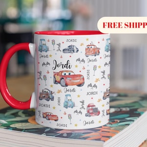 May include: A white ceramic mug with a black handle and the text "But First, Coffee" in a handwritten style. The mug is on a white surface. The mug is approximately 4 inches tall.