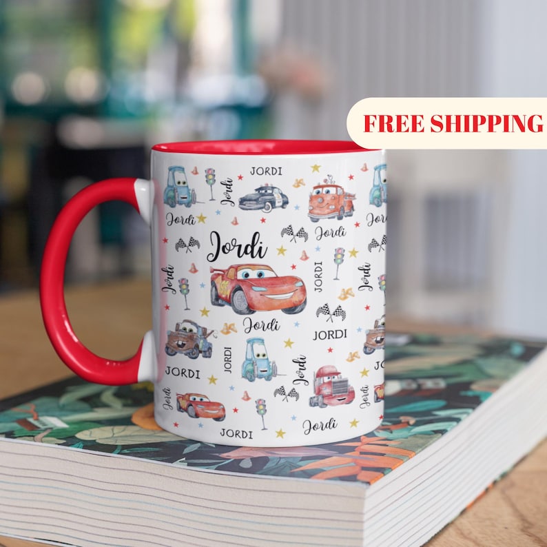 May include: A white ceramic mug with a black handle and the text "But First, Coffee" in a handwritten style. The mug is on a white surface. The mug is approximately 4 inches tall.