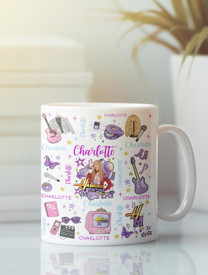 K&ouml;nnte beinhalten: Wei&szlig;e Keramiktasse mit einem farbenfrohen Design mit dem Namen "Charlotte" und verschiedenen Illustrationen. Das Design umfasst eine Gitarre, ein Mikrofon, Schmetterlinge und einen Fernseher. Die Tasse hat einen wei&szlig;en Griff.